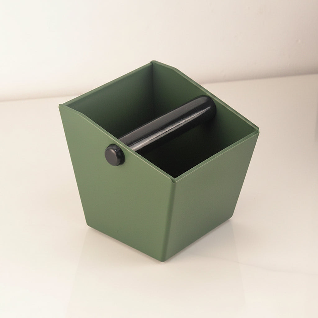 Green coffee knockbox with a warm white background.
